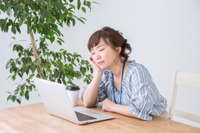 食後の眠気に襲われる女性